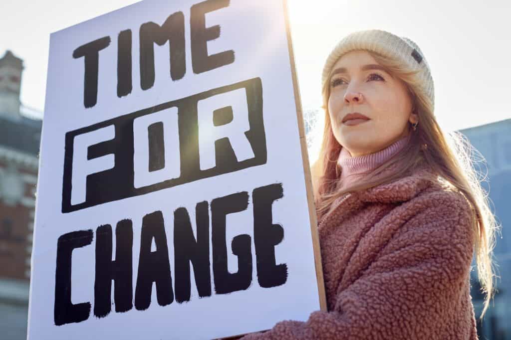 Female Protestor On Demonstration March Holding Time For Change Placard